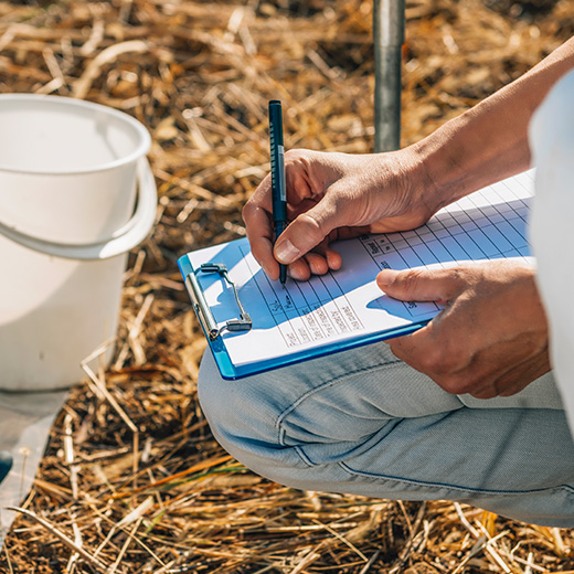Contractor writing notes on a clipboard during an outdoor pond inspection